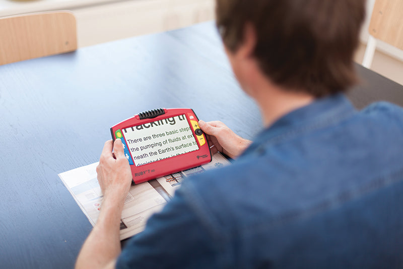 Viewing man holding the RUBY 7 HD while magnifying text from a book