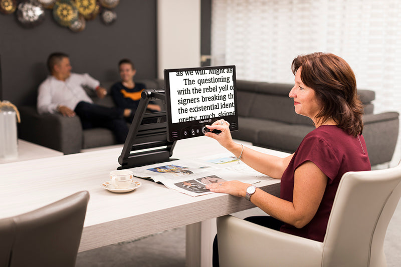 women magnifying newspaper and displaying white text on black background with clearview go